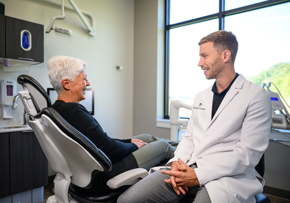 dr_greg_speaking_with_patient_in_chair Dr. Cochrane with dental implants patient.